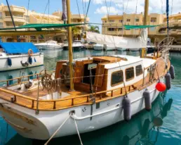 Velero clásico de madera amarrado en Puerto Marina de Benalmádena, con cubierta de teca y timón de rueda