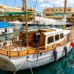 Velero clásico de madera amarrado en Puerto Marina de Benalmádena, con cubierta de teca y timón de rueda