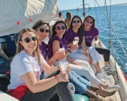 Group of women in matching purple shirts seated on the yacht's deck with drinks