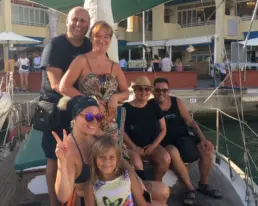 Family group posing on the deck of a yacht moored in the harbour