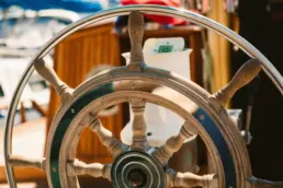 Close-up of a yacht's wooden ship's wheel with turned spokes and a brass hub