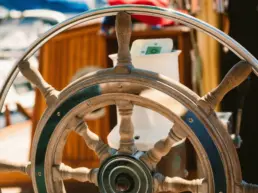 Close-up of a yacht's wooden ship's wheel with turned spokes and a brass hub