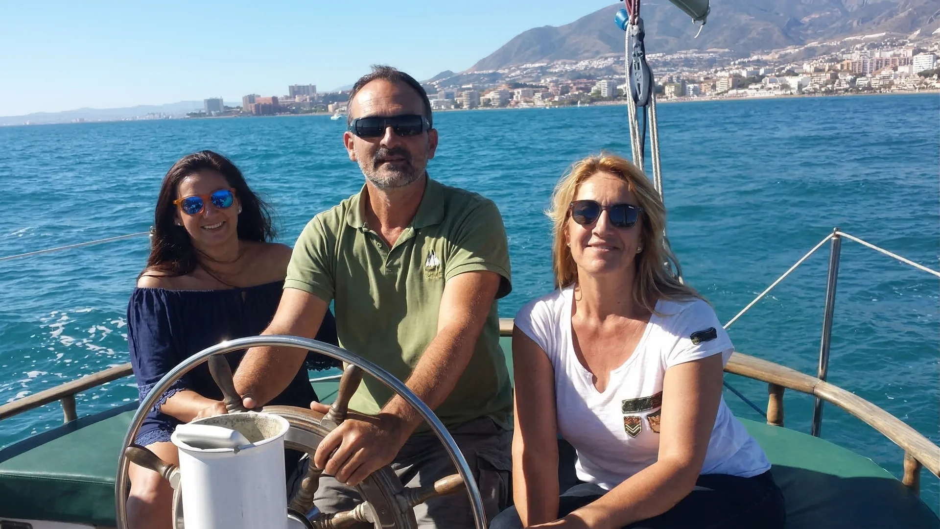 Passager à la barre aux côtés du skipper, regardant l'horizon pendant une sortie en voilier à Benalmádena